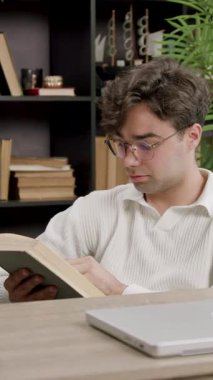 Young specialist reads a book in his free time from work using free time effectively for brain and new knowledge. Boy lectures a book at work in a modern office. Modern conditions for employees