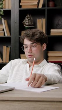 Dizüstü bilgisayarın önünde sandalyede oturan serbest çalışan çocuk ekranda gördüklerinden memnun değil ve hayal kırıklığına uğruyor. Genç adam çalışmalarının sonuçlarına üzüldü. uzak görev