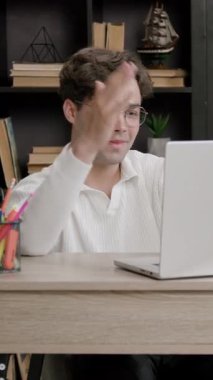 Erkek öğrenci çevrimiçi bilgisayar derslerine uzaktan katılıyor. Genç adam görüşünü öğretmenlerine ifade etmek için elini kaldırır. Çevrimiçi uzaklık öğrenimi