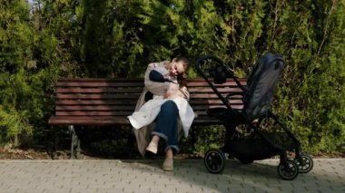 Bir kadın parkta bir bebeği sevgiyle tutuyor, sıcaklığı ve sevgiyi vurguluyor, kamera yavaş yavaş duygusal bağı yakalamak için yakınlaşıyor.