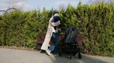 Bej ceketli bir kadın, bir çocuğu bebek arabasından sevgiyle kaldırır, hassas bir anı gösterir, kameranın hareketli bir şekilde takip etmesi, sahnenin sıcaklığını ve samimiyetini arttırır.