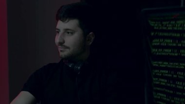 Erkek yapay zeka mühendisi, çevresindeki aydınlatma ve dijital ekranlarla çevrili olan çalışma yerinde kodlama yapmakla son derece meşgul.