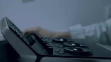 Gösterişli bir ses cihazının kontrollerini ustalıkla ayarlayan, karmaşık doku ve materyalleri vurgulayan, sahnenin hassasiyetini ve bağlılığını artıran kademeli bir zoom ile odaklanmış bir elin yakın plan çekimi.