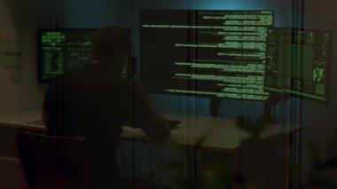 Kendini adamış bir programcı, yeşil metinli birden fazla ekranla çevrili bir kodlama oturumuna katılır. Bu oturum, büyüleyici teknoloji atmosferini ve çalışma akışını gözler önüne serer.