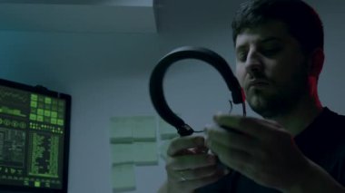 Siber güvenlik analisti verilerle dolu bilgisayar ekranına bağlanıyor, odaklanmayı arttırmak için kulaklık takıyor, siber güvenlik çalışmalarının büyüleyici atmosferini gösteriyor