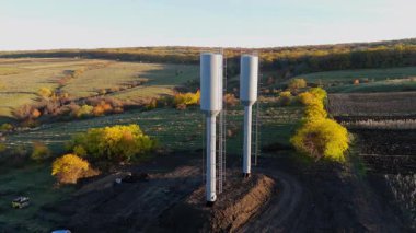 Renkli sonbahar ağaçlarıyla çevrili iki su kulesi manzaraya hükmediyor. Kameralar manzarayı yakalamak için pürüzsüz bir şekilde uzaklaşıyor.
