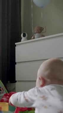 Bebek renkli oyuncaklarla dolu neşeli bir alanı keşfediyor, güneş ışığı sahneyi aydınlatıyor, sıcak ve davetkar bir atmosfer yaratıyor, kamera hareketi takip ediyor