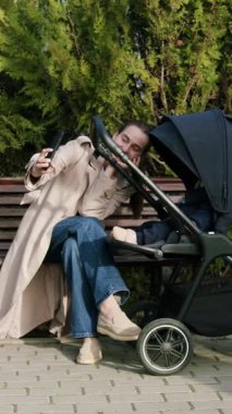 Bej ceketli kadın bakıcı, bir park bankında bebek arabasıyla çarpışır, sıcaklığı ve sevgiyi vurgular, duygusal bağlantı ve sahne ilerlemesini yakalamak için kamera tavaları