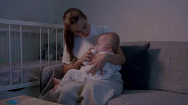 Bir anne, burun temizliği sırasında mızmız bebeğini rahatlatır. Bebeğini nazikçe tutarken aynı zamanda salin spreyi kullanır.