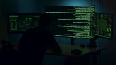 Siber güvenlik uzmanı bilgisayar korsanlığı faaliyetlerine daldı. Kodlarla dolu ekranlardaki verileri analiz etti. Kamera giderek artan gerilimi yakalamak için yakınlaştı.