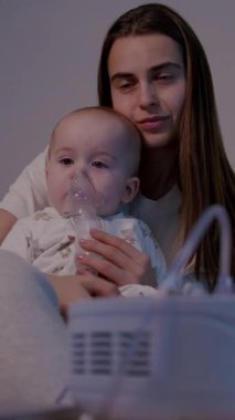 Bir anne bebeğini solunum terapisi sırasında kucaklar, besleyici bir ortam yaratır, aralarındaki bağı vurgular, birlikte geçirdikleri anı pürüzsüz bir şekilde yakalar.