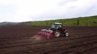Tohum matkabıyla donatılmış kırmızı bir traktör, ekme sürecini ve tarım makinelerinin etkin kullanımını gösteren geniş bir alanda ilerler.