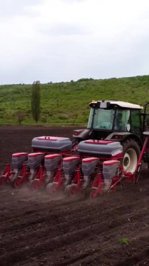 Tohum ekme makinesiyle donatılmış bir tarım traktörü, tohum tohumlarını hazırlanmış toprağa yerleştiriyor, ekme sürecini ve hareket halindeki makineleri gösteriyor.