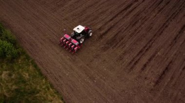 Tohum ekme makinesiyle donatılmış bir traktör tarladaki tohumları eker, geniş arazide tarımsal uygulamaları ve makineleri çalışır halde gösterir.
