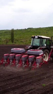 Tohum matkabıyla donatılmış bir traktör, tohumu verimli bir şekilde hazırlanmış toprağa yerleştirir. Bu da arazide hareket halindeki tarım tekniklerini ve makineleri gösterir.