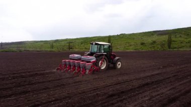 Tohum matkabı ile donatılmış bir tarım traktörü, tohum ekme tekniğini ve toprak etkileşimini gösteren iyi sürülmüş bir alana verimli bir şekilde tohum eker.
