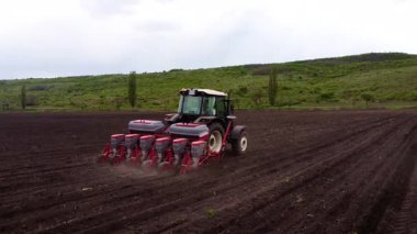 Tohum matkabıyla donatılmış bir traktör tarlada düzenli bir şekilde hareket eder. Bu sırada tohum eker, toprak ve toz toprağı tekmeler.