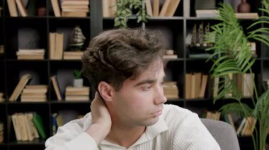 Masada oturan genç beyaz çocuk, kitaplıklar ve arka planda görünen bitkilerle ifadelerin ilerleyişini gösteriyor.