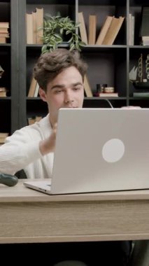 Masadaki öğrenci, iyi düzenlenmiş bir çalışma alanında, kitaplarla ve kırtasiyelerle çevrili bir dizüstü bilgisayarla etkileşime geçiyor.