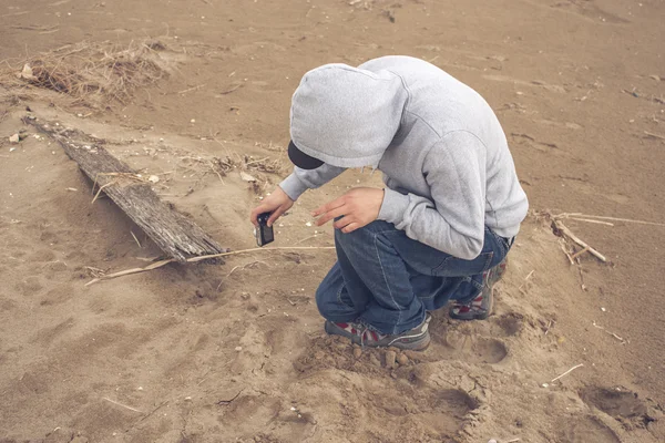 Sahilde bir hoodie ve bir beyzbol şapkası giyen genç adam