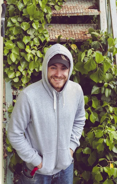 Mutlu genç adam bir hoodie ve bir beyzbol şapkası giyiyor