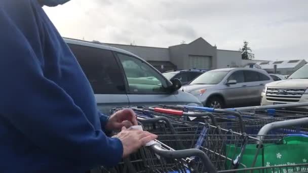 Klient dezynfekuje rękojeść wózka Walmart chusteczkami alkoholowymi — Wideo stockowe