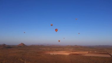 Şafak vakti Phoenix, Arizona yakınlarındaki renkli sıcak hava balonlarına doğru uçuyorlar.