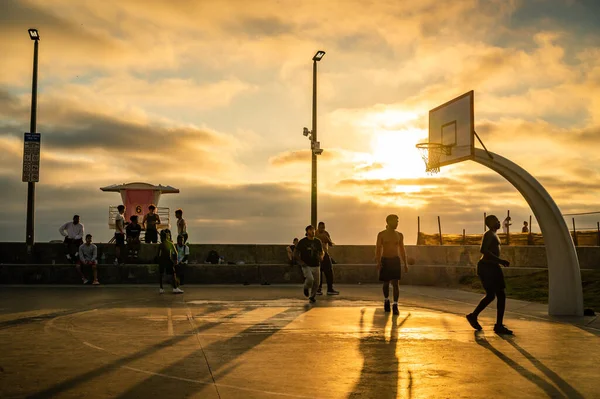 Hombres jugando baloncesto en una puesta de sol al aire libre de la cancha de baloncesto — Foto de Stock