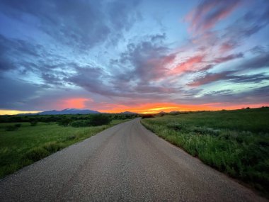 Otlaktan geçerek uzaklığa doğru giden yol. Güzel günbatımı muson gökyüzü