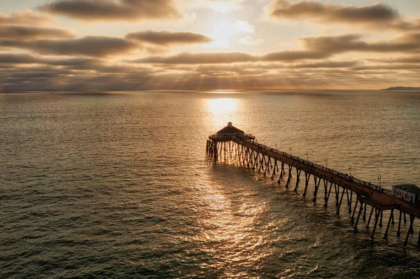 Beautiful sun rays and golden light on ocean and pier — Stock Photo, Image