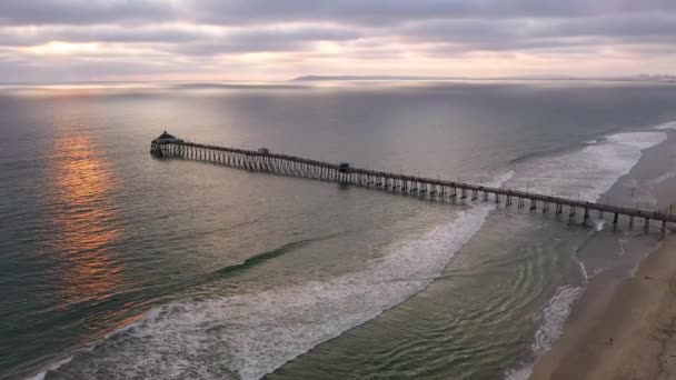 Dramatische antenne van Imperial Beach Pier met zonlicht reflecterend op de oceaan — Stockvideo