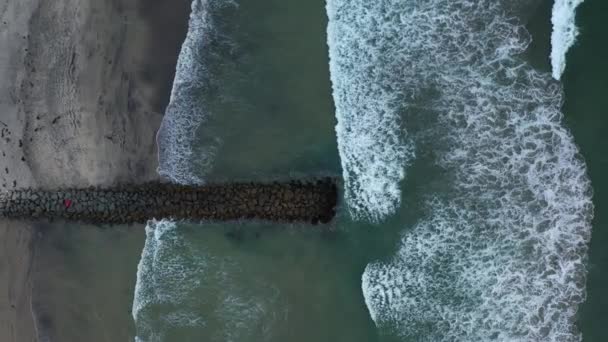 Vedere deasupra dronei de sus în jos a jetty cu valuri de rupere, zoom out — Videoclip de stoc
