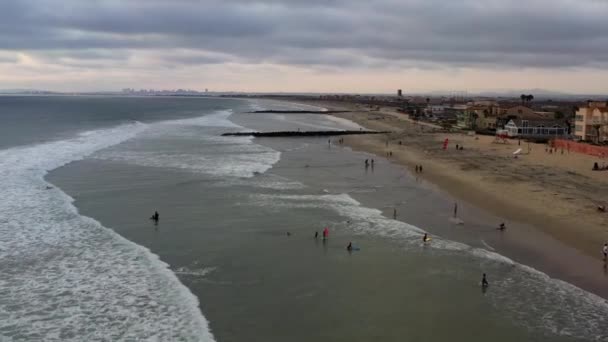 Surfers in de oceaan door steiger in Imperial Beach San Diego California, luchtfoto 4k — Stockvideo