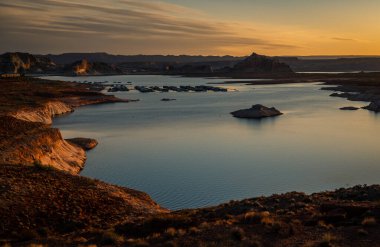 Güneş doğarken Powell Gölü 'nü çevreleyen büyüleyici bir manzara silueti.