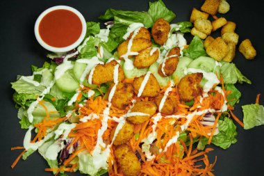 Salatalı salata, salatalık, havuç, kızarmış tavuk, kızarmış ekmek, çiftlik sosu ve salsa sosu. Zarafet ve sıcaklıkla düşük ışık reklamı..