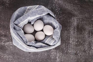 Tekstil arka planında tavuk yumurtası. Gri-mavi arka planda beyaz yumurtalar