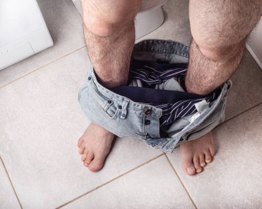 Pantolonu fayans zemininde yatan bir adamın bacakları. Erkek sağlığı konsepti, dramatik geçmiş