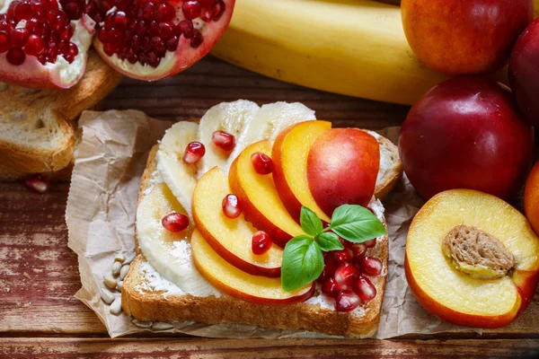 Healthy Breakfast. Dessert. Toast with cream cheese, banana, peach, nectarine and pomegranate