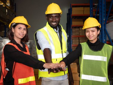 Bir grup depo çalışanı ellerini birliğin, takım çalışmasının ve şirketteki iyi bir işbirliği motivasyonunun gücünü gösteren bir yığın el ile bir araya getiriyorlar.