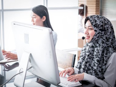 Güzel bir Müslüman gümrük memuru, müşterilerine işyerinde danışmanlık yaparken ve onlara yardım ederken özgüvenle gülümser..