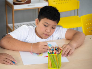 Tekerlekli sandalyedeki engelli çocuk evde geliştirme egzersizlerinin keyfini çıkarırken resim yapmayı ve resim yapmayı öğreniyor. Eğitim ve özel çocuk kavramı.