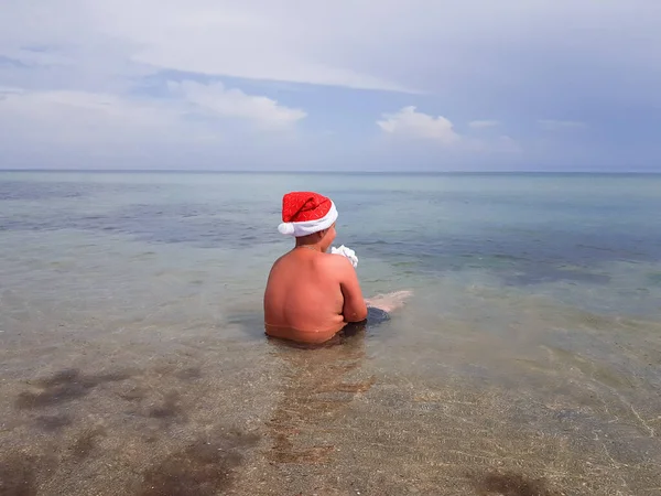 Homem Imagem Papai Noel Chapéu Festivo Está Sentado Praia Olhando — Fotografia de Stock