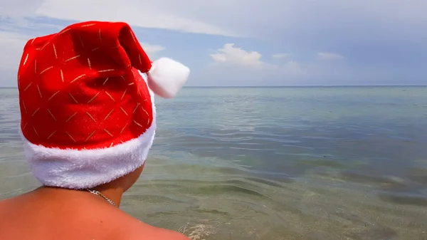 Noel Baba Şapkalı Bir Adam Sahilde Denizde Oturuyor Denizde Yılbaşı — Stok fotoğraf