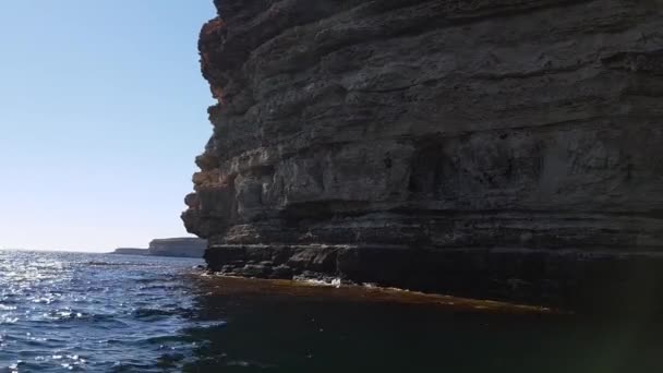 Eine bergige Küste mit steilen Felsklippen und Büschen vor dem Hintergrund des Meeres unter den Wolken. Das Video wurde von einem Boot aufgenommen. — Stockvideo