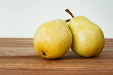 Tahta bir masada iki olgun sarı armut, seçici bir odak