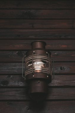 Açık hava feneriyle retro-stil ışık. Ahşap bir duvarda eski bir fener. dikey fotoğraf. Kahverengi ahşap duvar