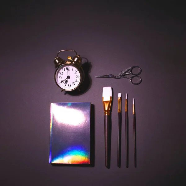 Big alarm clock, brush set, scissors and holographic notepad — Stock Photo, Image