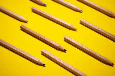 Parlak sarı arka planda renkli tahta kalemlerin deseni