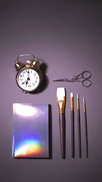 Dikey gri arkaplanda altın alarm saati ve holografik not defteri — Stok fotoğraf