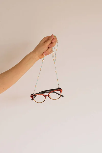 Egy női kéz szemüveg tartását tartja egy kézzel készített láncon. — Stock Fotó